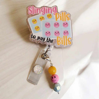 Interchangeable Badge Reel Charm: Slinging Pills To Pay The Bills. Our Interchangeable Badge Reel Charms are made to be used with our Interchangeable Badge Reels. RSV|66316