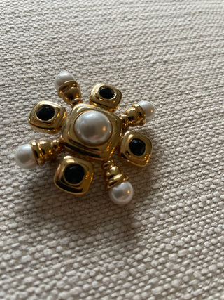 vintage St. John gold-tone brooch features black cabochons and faux pearls arranged in a starburst or Maltese cross design.