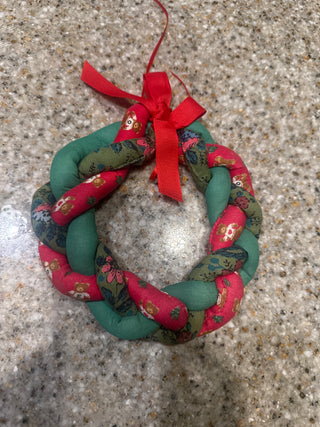 vintage handmade braided fabric Christmas wreath, often crafted with stuffed fabric tubes and a decorative red bow