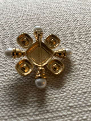 vintage St. John gold-tone brooch features black cabochons and faux pearls arranged in a starburst or Maltese cross design.